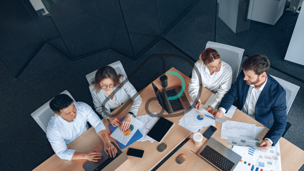 Team collaborating on creating a digital roadmap for business growth with laptops, charts, and documents in a modern office setting.