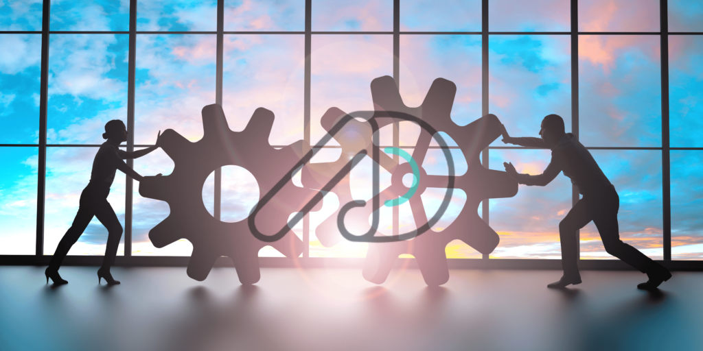 Silhouettes of a man and woman pushing large interlocking gears in an office setting with a sunset view through glass windows. Concept representing teamwork and efficiency in IT consulting companies.