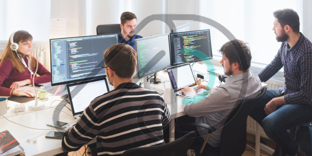 A team of developers and data specialists collaborating in an office setting, with lines of code visible on multiple monitors. This image depicts the work of SEO companies in United States.